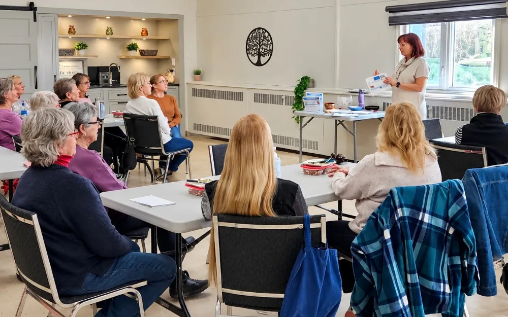 Une animatrice présente un atelier Énergie et bien-être à un groupe assis autour de tables, au Centre Charles-Émile Claude